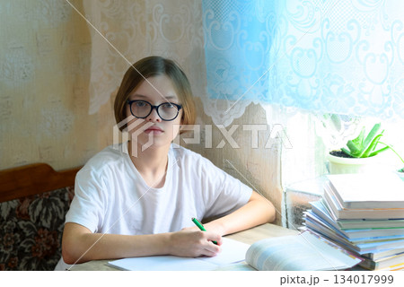 schoolboy in glasses with a pen in his hand looks straight at the camera schoolboy in glasses with a pen in his hand looks straight at the camera 134017999