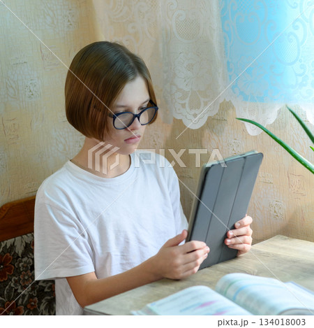 student in glasses uses a tablet for distance learning 134018003