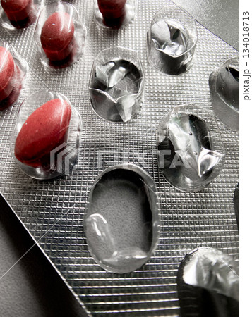 Red pills remaining in a blister pack with several empty slots, conceptualizing health, medication availability, treatment adherence, medical industry and wellness support Red pills remaining in a blister pack with several empty slots, conceptualizing health, medication availability, treatment adherence, medical industry and wellness support 134018713