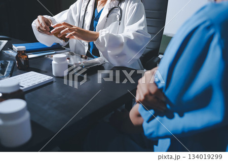 Female doctor holding a medicine bottle is checking the quality of medicine for any side effects the patient or not and recording patient information at the hospital. medical and health care concept Female doctor holding a medicine bottle is checking the quality of medicine for any side effects the patient or not and recording patient information at the hospital. medical and health care concept 134019299