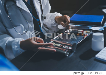 Female doctor holding a medicine bottle is checking the quality of medicine for any side effects the patient or not and recording patient information at the hospital. medical and health care concept 134019300