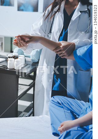 Doctor examining patient's elbow in hospital room Doctor examining patient's elbow in hospital room 134019323