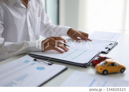A man signing a contract for a car loan, lease, vehicle registration or insurance policy. Concept for Sales Contract, Financing Agreement, Insurance Policy, Vehicle Registration. 134020323