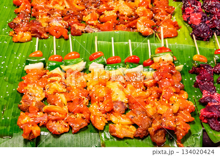 grilled meat on wooden skewers on banana leaves, street food, selective focus 134020424