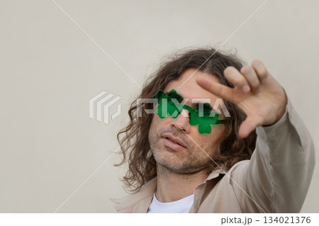 Stylish caucasian adult man 30s wearing green novelty sunglasses. Playful fashion portrait with creative gesture, isolated background, st patricks day concept. 134021376
