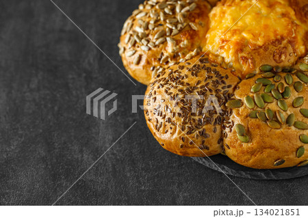Bun with sunflower seeds flax and pumpkin on slate stone plate round, dark background, selective focus 134021851