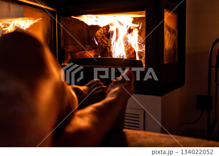 Woman's feet in front of the fireplace. Woman warms herself by the fire 134022052
