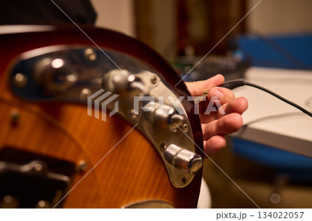 Musician setting up equipment, Preparing bass guitar for recording, Electric bass player organizing gear in studio, Closeup of musician tuning and adjusting bass instrument Musician setting up equipment, Preparing bass guitar for recording, Electric bass player organizing gear in studio, Closeup of musician tuning and adjusting bass instrument 134022057