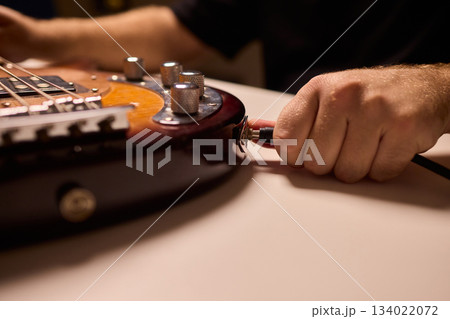 Musician setting up equipment, Preparing bass guitar for recording, Electric bass player organizing gear in studio, Closeup of musician tuning and adjusting bass instrument Musician setting up equipment, Preparing bass guitar for recording, Electric bass player organizing gear in studio, Closeup of musician tuning and adjusting bass instrument 134022072