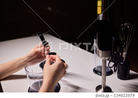 Preparing blender on kitchen counter, Scene shows detailed process of assembling immersion blender, Cozy kitchen scene of hands carefully putting together blending device 134022079