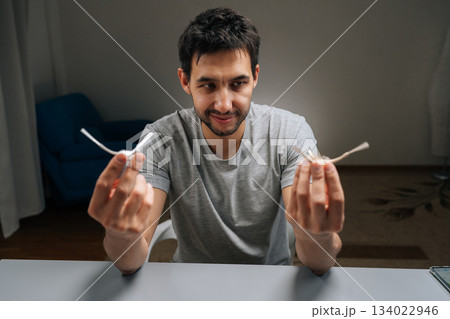 Portrait of male holding in hand and examining tangled dirty side brush from robot vacuum, illustrating maintenance, replacement and improved smart home cleaning efficiency and hygiene. Portrait of male holding in hand and examining tangled dirty side brush from robot vacuum, illustrating maintenance, replacement and improved smart home cleaning efficiency and hygiene. 134022946