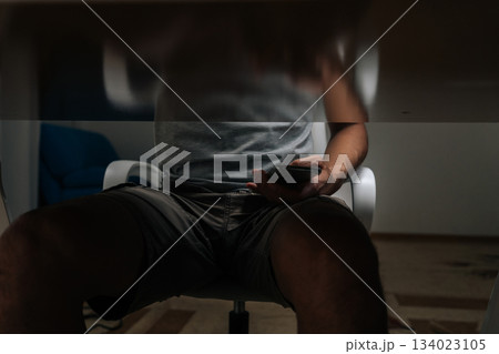 Student covertly referencing smartphone beneath desk as cheat sheet during an exam, exhibiting academic dishonesty and attempting to get unfair advantage by concealing device, close-up. Student covertly referencing smartphone beneath desk as cheat sheet during an exam, exhibiting academic dishonesty and attempting to get unfair advantage by concealing device, close-up. 134023105