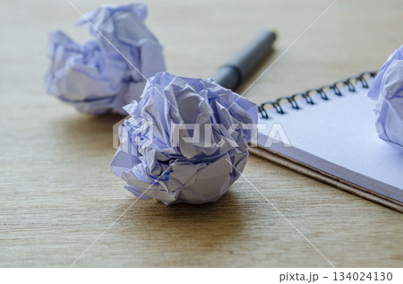 A focused view of a single crushed paper ball near a metallic ruler, emphasizing detail, texture, and the theme of discarded drafts or decisions. A focused view of a single crushed paper ball near a metallic ruler, emphasizing detail, texture, and the theme of discarded drafts or decisions. 134024130