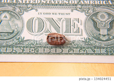 Close-up of a cracked coffee bean resting on a U.S. one-dollar bill 134024451