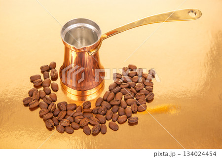 Traditional copper cezve with a golden handle next to a heap of coffee beans, Traditional copper cezve with a golden handle next to a heap of coffee beans, 134024454