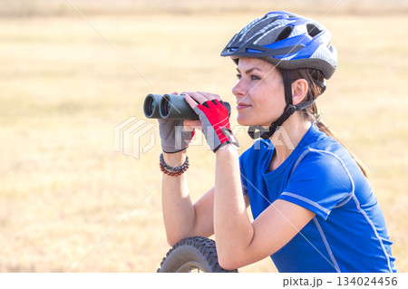 Beautiful woman cyclist looking through binoculars. Sports and recreation 134024456