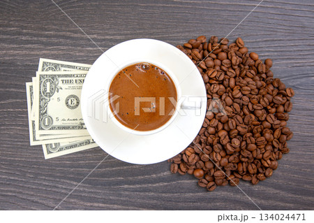 cup of coffee with fresh beans and a touch of cash on a wooden table. coffee business 134024471