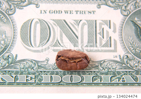 cracked coffee bean sits atop a U.S. one-dollar bill, blending natural brown hues cracked coffee bean sits atop a U.S. one-dollar bill, blending natural brown hues 134024474