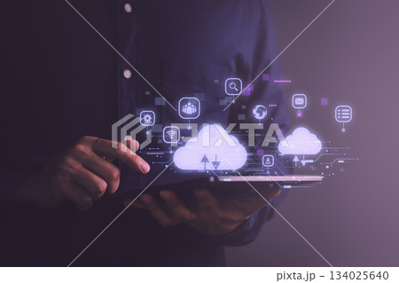 Man using digital tablet with holographic cloud computing icons, representing data storage, online communication, digital technology, upload and download, cloud services, and internet connectivity. 134025640