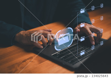 Close-up of hands using laptop with virtual digital folders and documents interface, symbolizing data management, file storage, cloud computing, organization, and modern information technology. 134025643