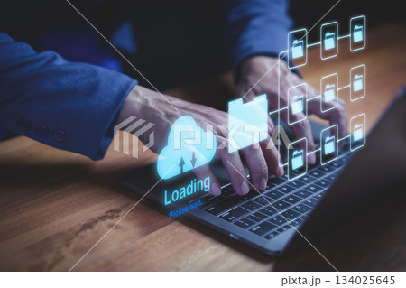 Businessman typing on laptop computer with holographic cloud storage and digital folders, representing data upload, cloud computing, file sharing, and online data management. Businessman typing on laptop computer with holographic cloud storage and digital folders, representing data upload, cloud computing, file sharing, and online data management. 134025645