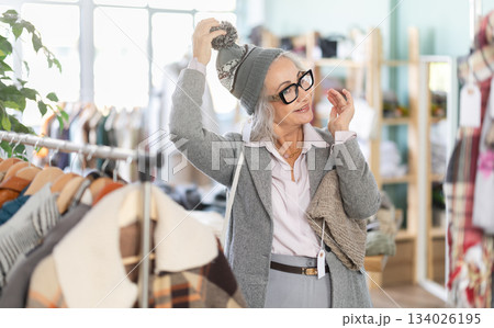 Mature woman in glasses choosing a warm hat 134026195