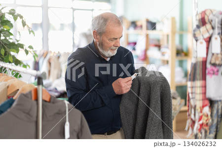 Elderly man choosing jersey knitted sweaters 134026232