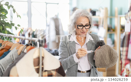 Family clothing store, senior woman customer choose winter head cover 134026259