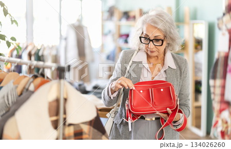 Family clothing store, senior woman customer choose handbag 134026260