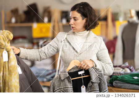 Elegance lady choosing stylish warm coat or jacket for winter season in clothing boutique 134026371