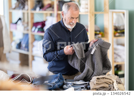Elderly man choosing jersey knitted sweaters Elderly man choosing jersey knitted sweaters 134026542