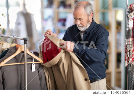 man chooses a brown jacket in a store 134026564
