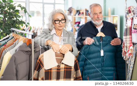 Family clothing store, senior couple customer chooses jacket or coat 134026630