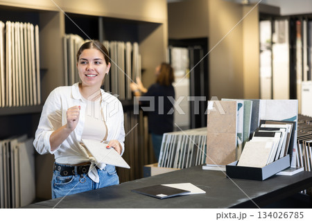 in hardware store,woman chooses ceramic tile with modern pattern for bathroom 134026785