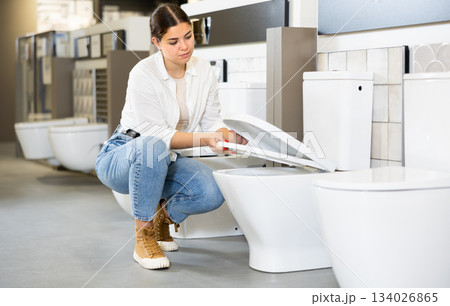 in plumbing department, female buyer checks for defects of toilet before purchasing toilet pan in plumbing department, female buyer checks for defects of toilet before purchasing toilet pan 134026865