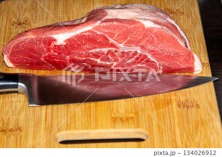 Piece of raw beef on a wooden cutting board. 134026912