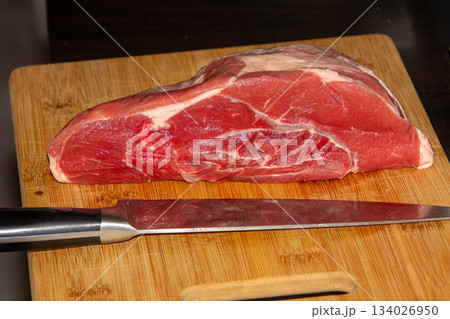 Piece of raw beef on a wooden cutting board. Piece of raw beef on a wooden cutting board. 134026950