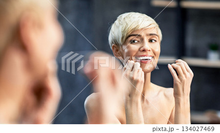 Dental Care. Mature Woman Flossing Teeth Doing Toothcare Routine Standing Wrapped In Towel In Bathroom At Home. Selective Focus 134027469