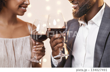 Black man and woman looking at each other and toasting with red wine, having dinner at restaurant, cropped Black man and woman looking at each other and toasting with red wine, having dinner at restaurant, cropped 134027491
