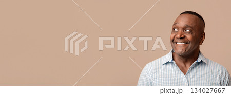 Wow. Positive middle aged african man looking aside at empty space, orange background, panorama Wow. Positive middle aged african man looking aside at empty space, orange background, panorama 134027667