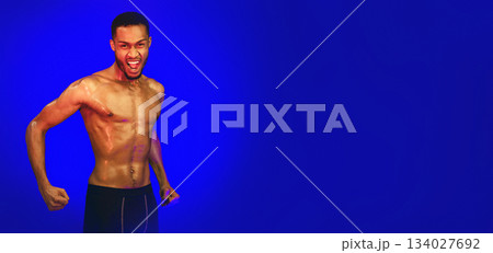 Aggressive Shirtless Black Fighter Guy Shouting Clenching Fists Ready To Fight Posing On Blue Background. Studio Shot Aggressive Shirtless Black Fighter Guy Shouting Clenching Fists Ready To Fight Posing On Blue Background. Studio Shot 134027692
