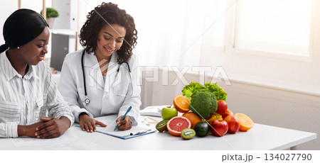African american woman dietologist taking female patient anamnesis, nutritionist consultation, copy space African american woman dietologist taking female patient anamnesis, nutritionist consultation, copy space 134027790