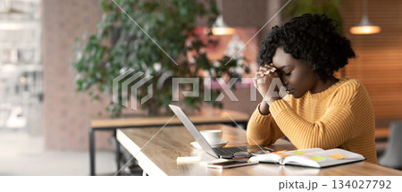 Fatigue black woman sitting in cafe, looking for job online, using laptop, having difficulties, empty space 134027792
