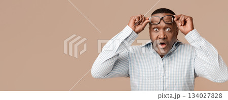 Unbelievable. Shocked mature african american man looking at camera, rising his eyeglasses up in shock Unbelievable. Shocked mature african american man looking at camera, rising his eyeglasses up in shock 134027828