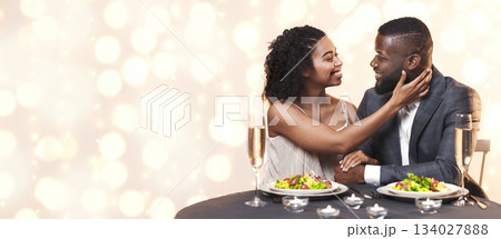 I love you. Attractive black woman touching her handsome man, cuddling in restaurant, having festive dinner together 134027888