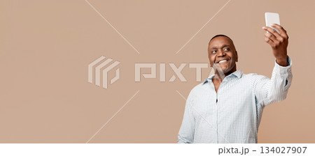 Handsome mature black man making selfie on cellphone and smiling, orange studio background 134027907