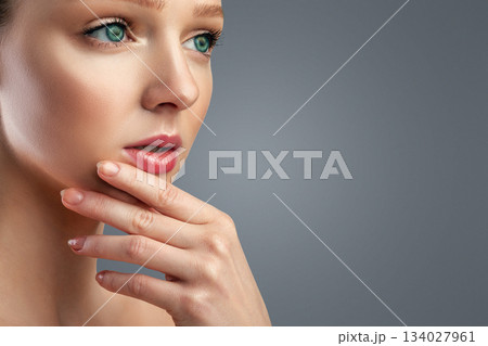 Facial Skincare. Pretty Young Woman With Perfect Makeup Posing Touching Chin And Looking Aside At Free Space For Text Over Gray Studio Background. Panorama, Cropped Facial Skincare. Pretty Young Woman With Perfect Makeup Posing Touching Chin And Looking Aside At Free Space For Text Over Gray Studio Background. Panorama, Cropped 134027961