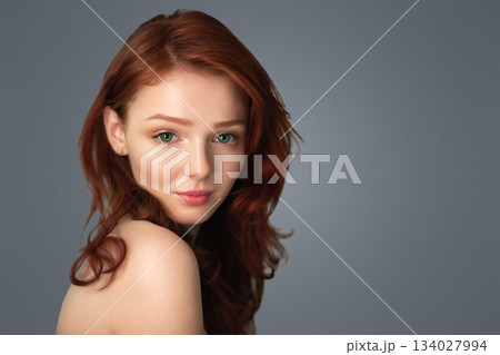Natural Beauty. Red-Haired Young Lady Posing With Green Plant Leaves Standing Over Gray Studio Background, Looking At Camera. SPA, Skin Beauty And Skincare Cosmetics Concept. Natural Beauty. Red-Haired Young Lady Posing With Green Plant Leaves Standing Over Gray Studio Background, Looking At Camera. SPA, Skin Beauty And Skincare Cosmetics Concept. 134027994