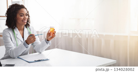 Food supplements concept. Afro woman doctor prescribing pills to female patient at her office Food supplements concept. Afro woman doctor prescribing pills to female patient at her office 134028002