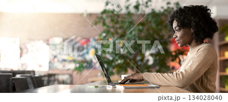 Young african woman working in cafe, using laptop, side view, empty space Young african woman working in cafe, using laptop, side view, empty space 134028040